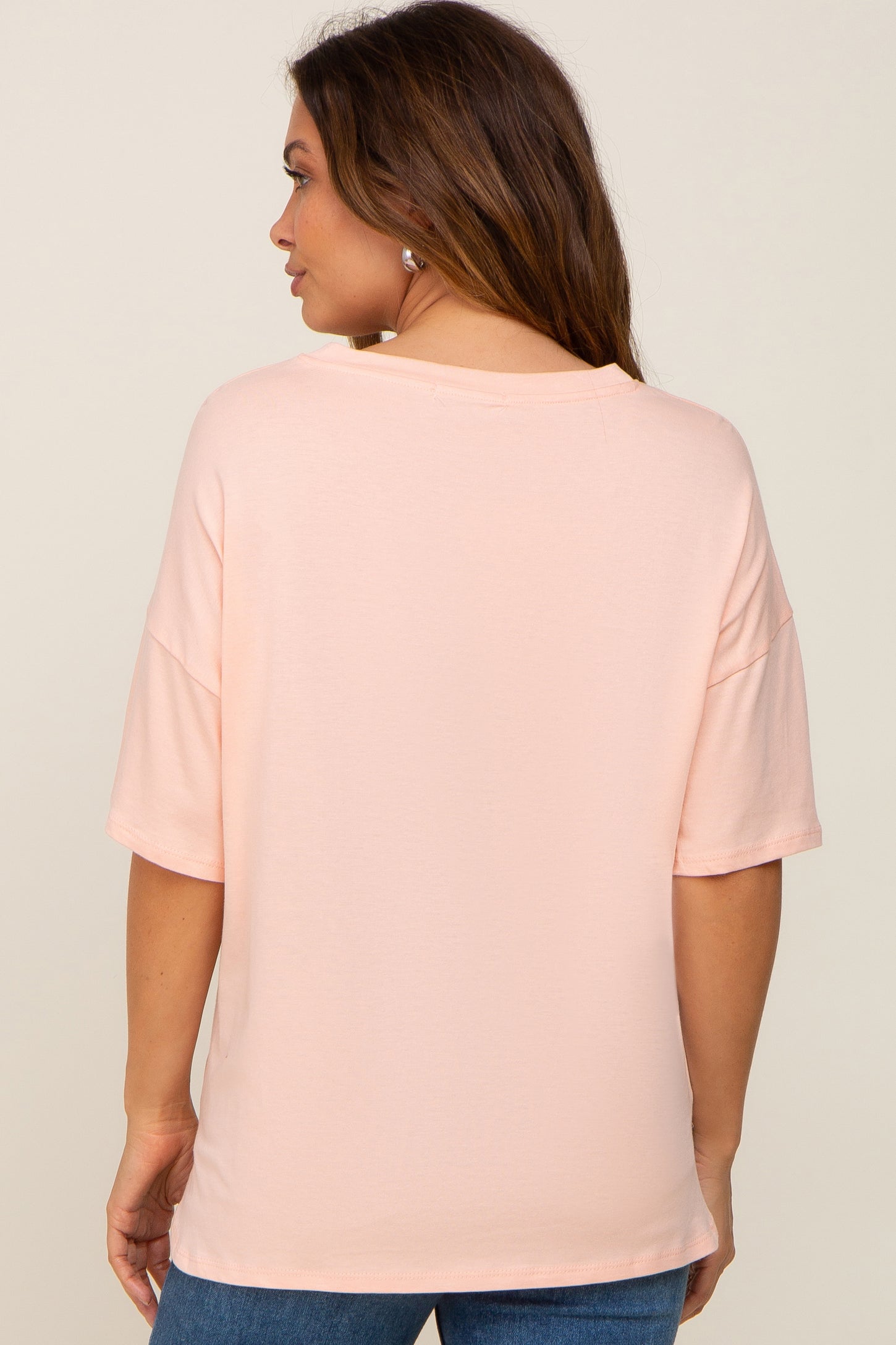 woman wearing a light pink maternity top with short sleeves and a relaxed fit, seen from the back