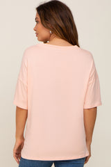 woman wearing a light pink maternity top with short sleeves and a relaxed fit, seen from the back