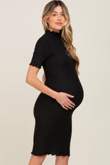 Pregnant woman wearing a black ribbed short sleeve maternity dress with a mock neck and lettuce trim.