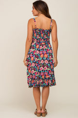 woman wearing a floral smocked maternity dress with straps and ruffled hem, showing her back view