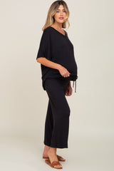 pregnant woman wearing black short sleeve maternity lounge set with wide leg pants and brown sandals
