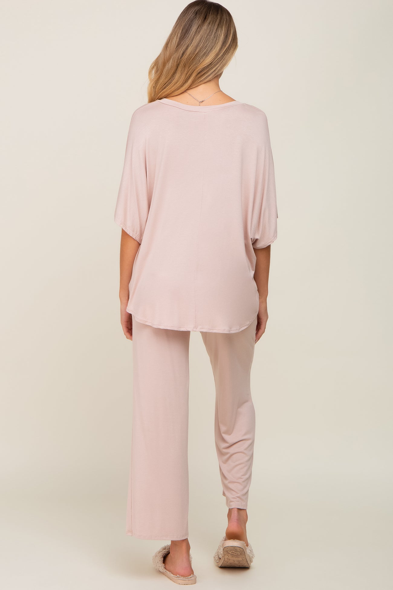 woman wearing a light pink maternity loungewear set with a loose top and relaxed fit pants