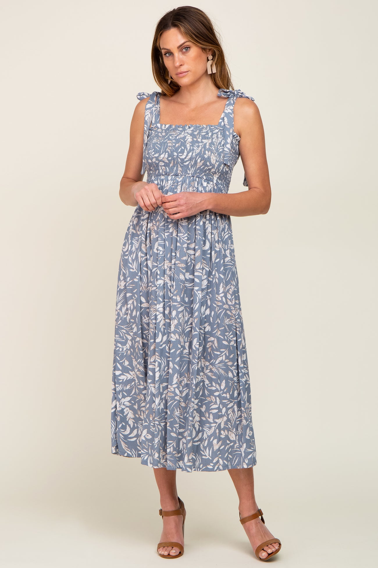 woman wearing a blue floral midi dress with tie straps and smocked bodice