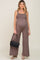 woman wearing a maternity brown smocked jumpsuit with wide legs and carrying a black handbag, baby bump visible