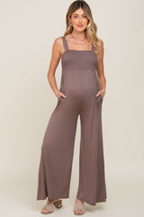 woman wearing a dusty mauve maternity jumpsuit with smocked bodice and pockets, showcasing her baby bump