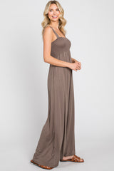 woman wearing a brown smocked bodice maxi dress with thin straps standing sideways