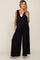 woman wearing a black maternity jumpsuit with wide legs and a v-neck, showcasing her baby bump