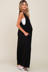 woman wearing a black sleeveless maternity maxi dress with pockets and a baby bump visible