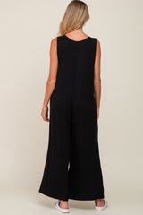 woman wearing a black sleeveless maternity jumpsuit, showing a relaxed fit and wide leg style from the back