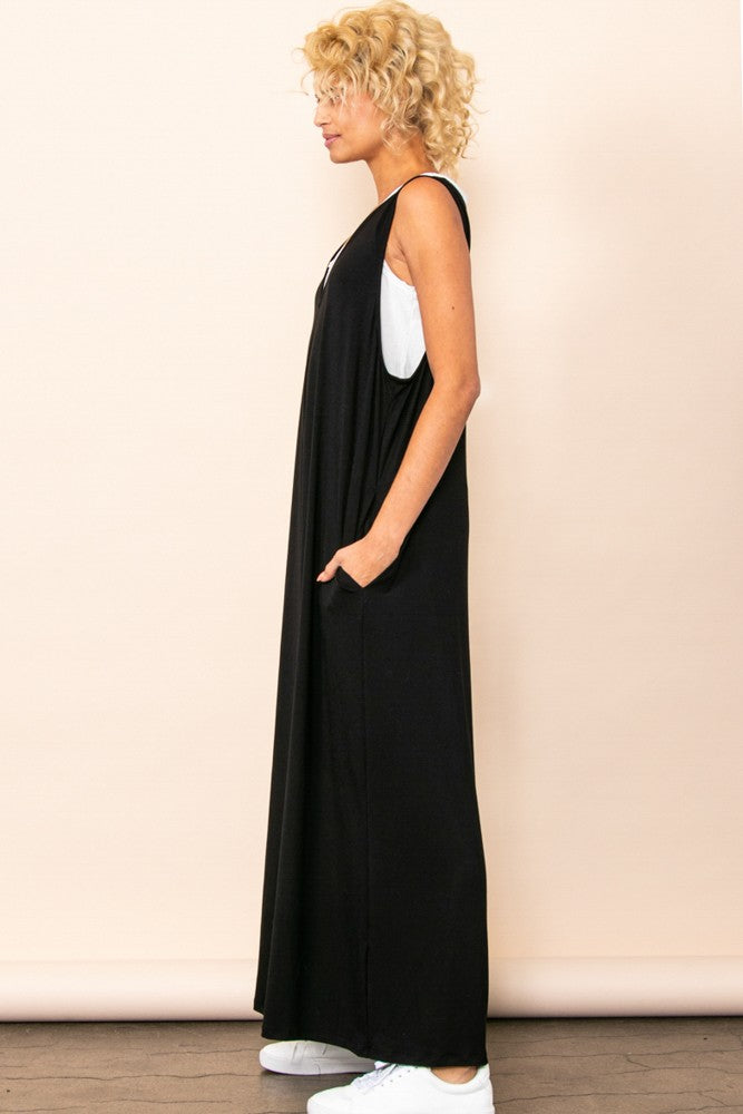 woman wearing a black sleeveless maxi dress with pockets and white sneakers