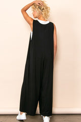 woman wearing a black sleeveless jumpsuit with a relaxed fit and open back, styled with white sneakers