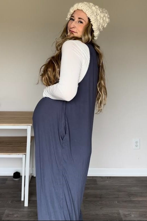 woman wearing a navy blue maternity dress with side pockets and a white long sleeve top, showcasing her baby bump