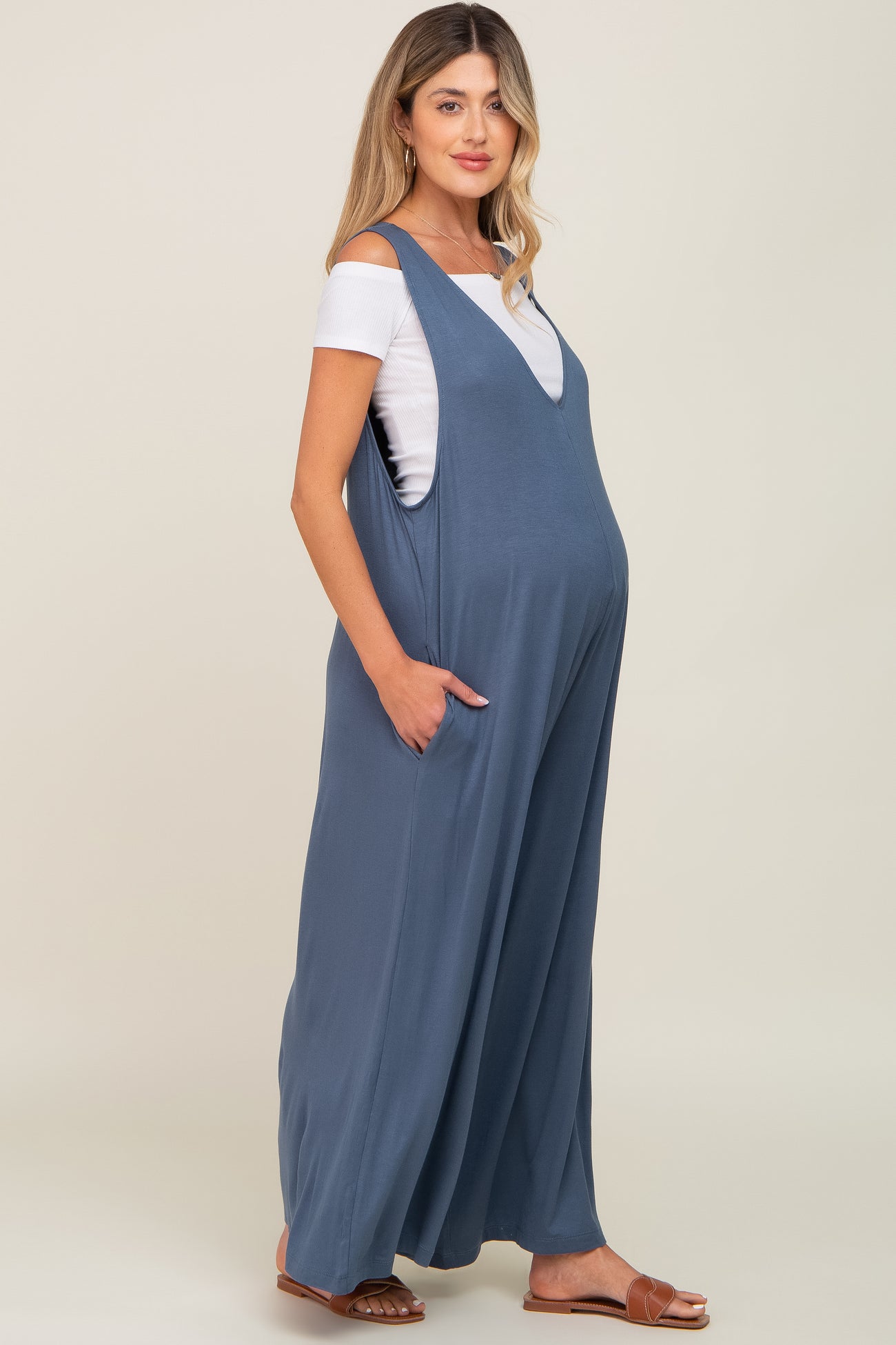 woman wearing a blue maternity maxi dress with pockets and a visible baby bump