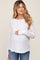 woman wearing a white long sleeve maternity top and holding her baby bump