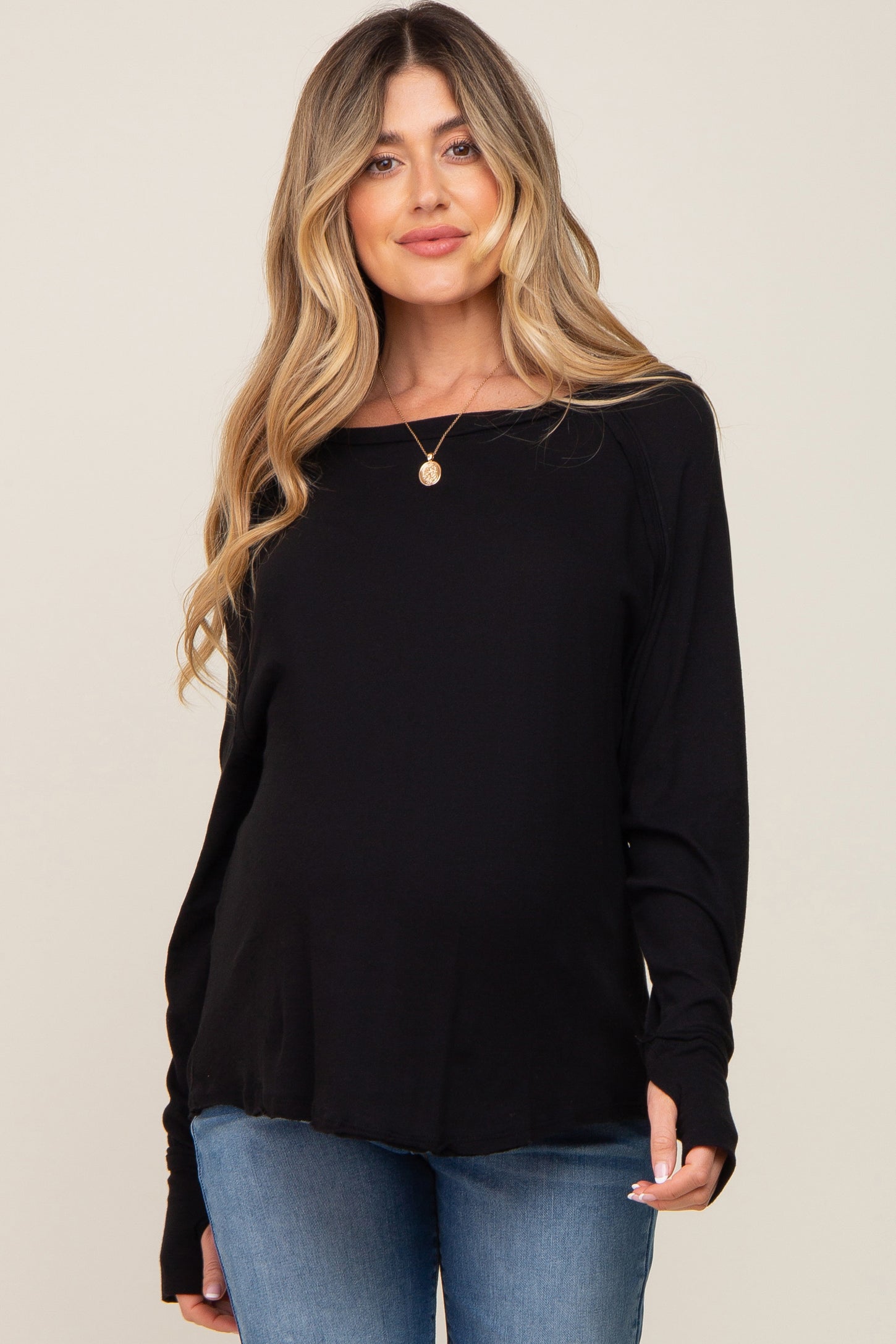 woman wearing a black long sleeve maternity top and showing her baby bump