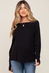 woman wearing a black long sleeve maternity top and showing her baby bump
