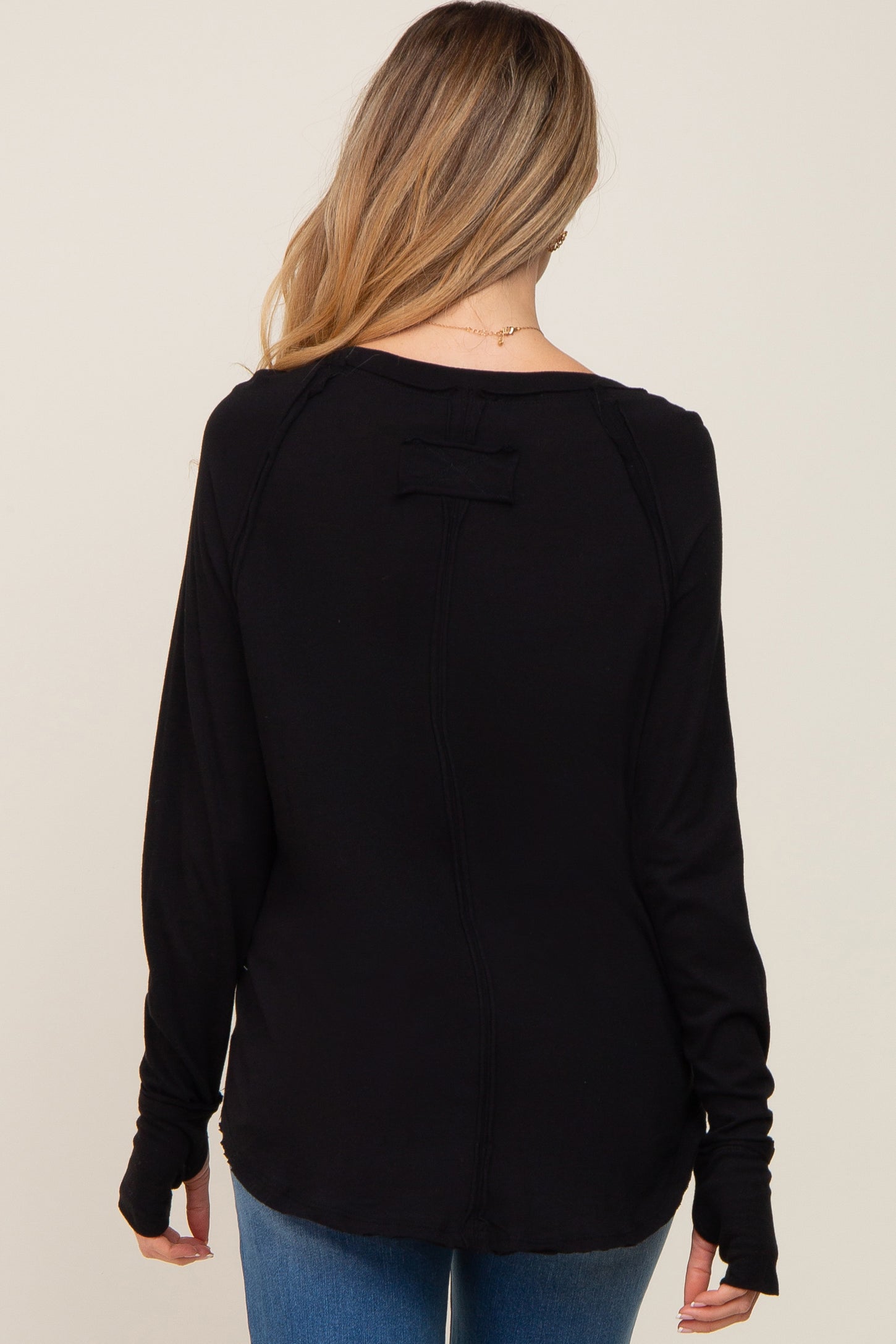 woman wearing a black long sleeve maternity top with a relaxed fit and back detail