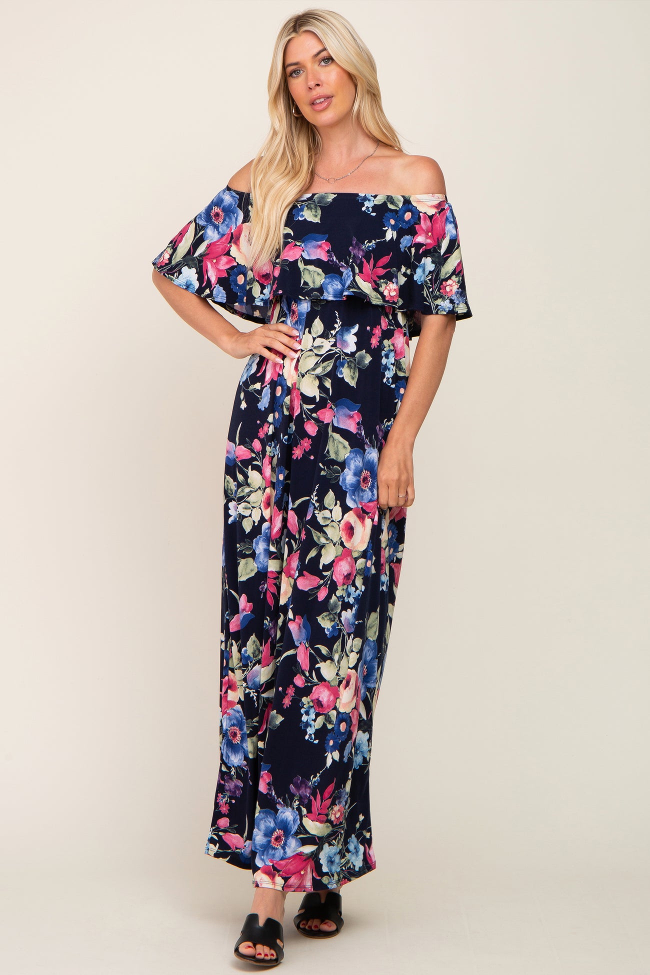 woman wearing a navy off-the-shoulder maxi dress with a vibrant floral print and flowing sleeves