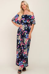 woman wearing a navy off-the-shoulder maxi dress with a vibrant floral print and flowing sleeves