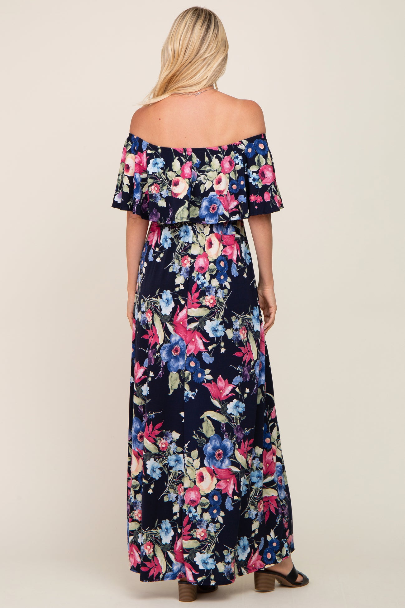 woman wearing a navy floral off-the-shoulder maxi dress, showing the back and flowing skirt detail