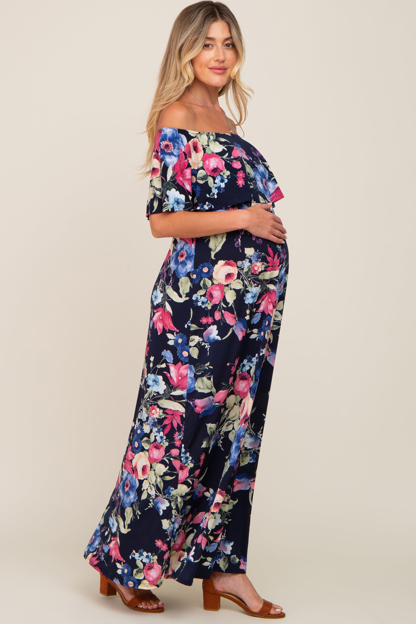 woman wearing a navy blue floral off-the-shoulder maxi dress, highlighting her baby bump