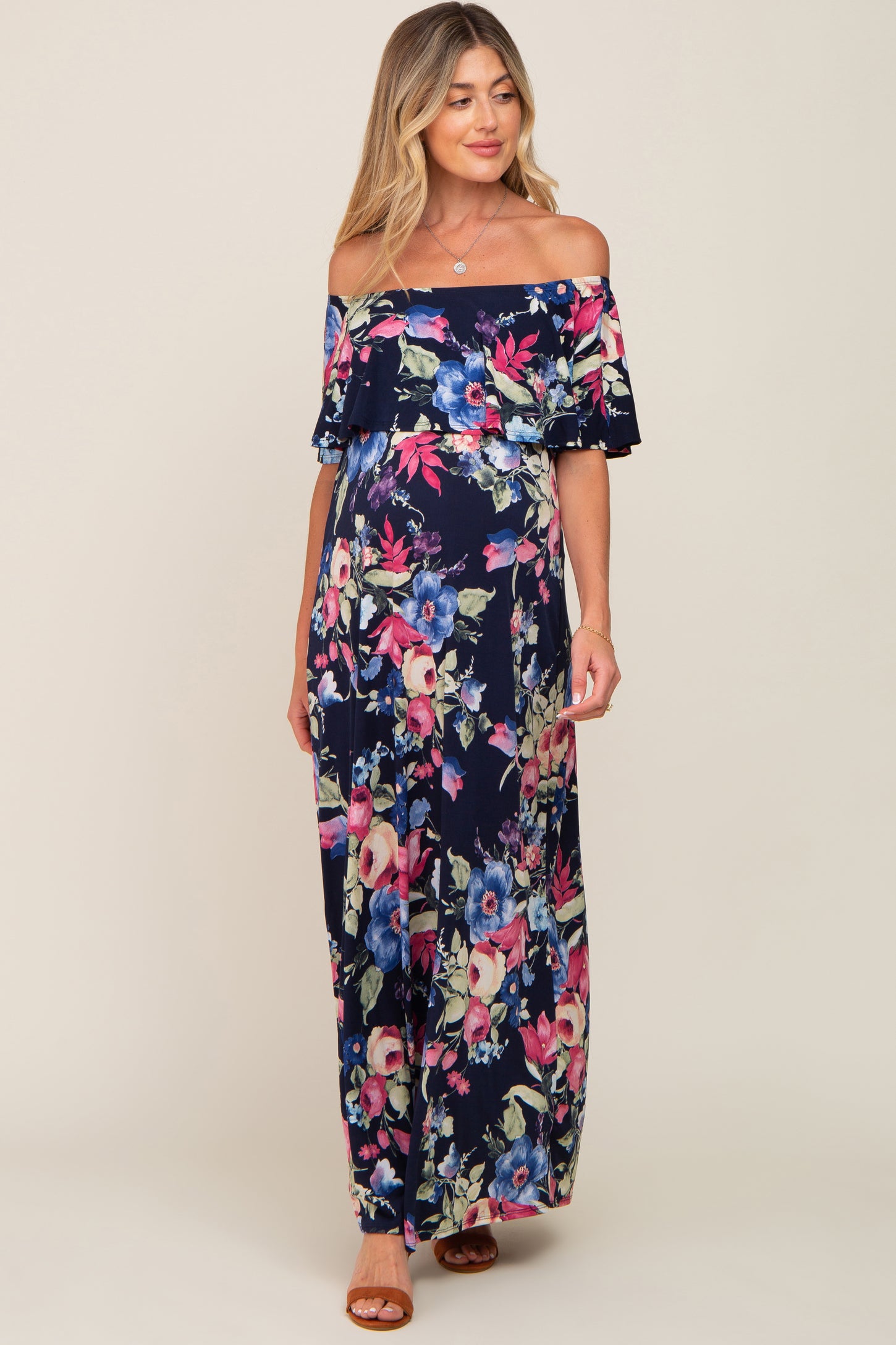 woman wearing a navy floral off-the-shoulder maxi maternity dress with a flowing silhouette and visible baby bump