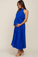 woman wearing a pleated royal blue maternity dress and holding her baby bump
