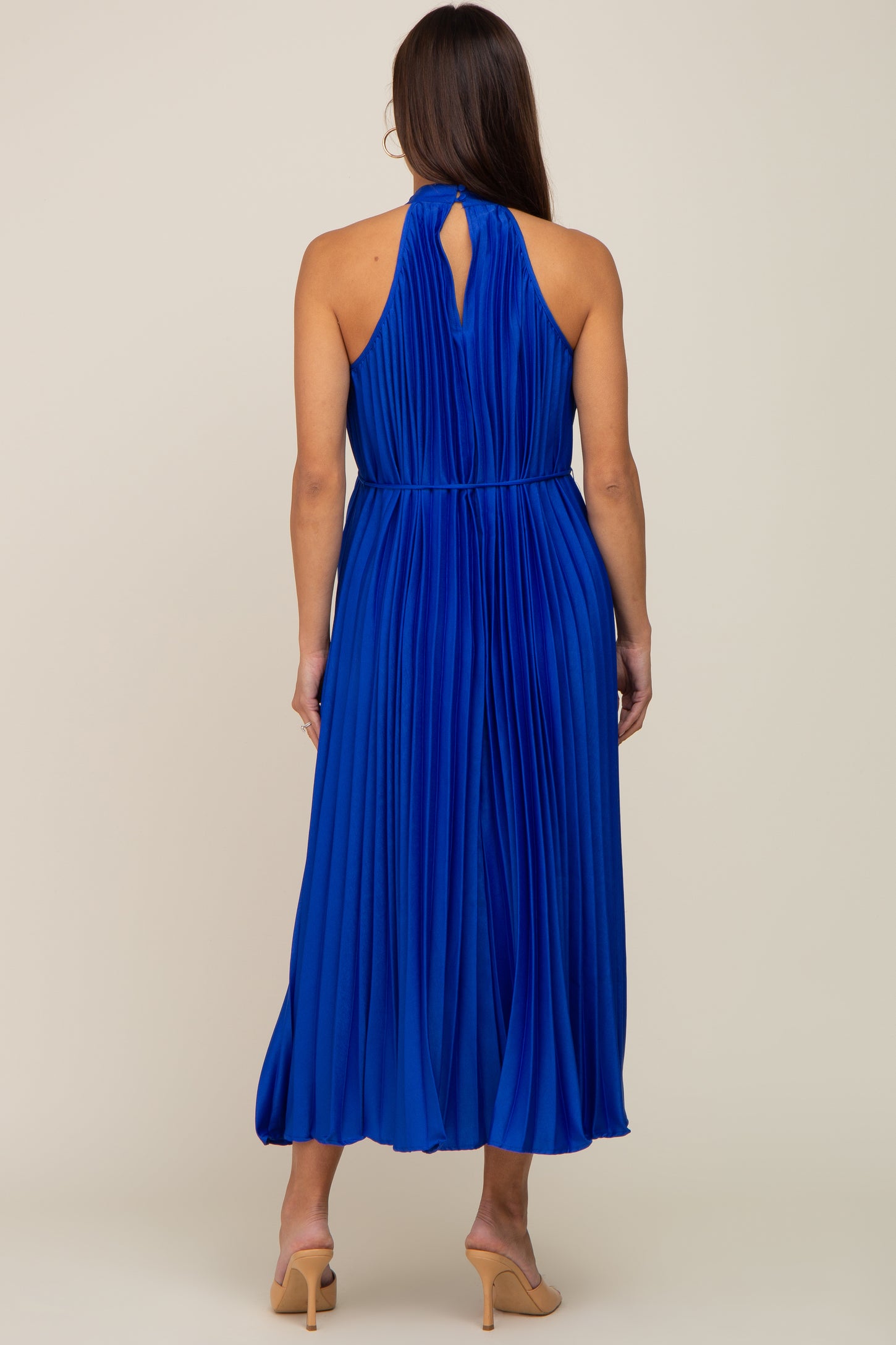 woman wearing a pleated royal blue maternity dress with a keyhole back detail