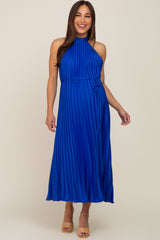 woman wearing a pleated royal blue maternity dress with a halter neck and tie waist, showcasing a baby bump