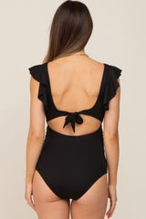 woman wearing a black maternity one-piece swimsuit with ruffled sleeves and a tie-back detail