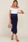 pregnant woman in white off-the-shoulder top and navy blue maternity midi skirt holding a tan handbag