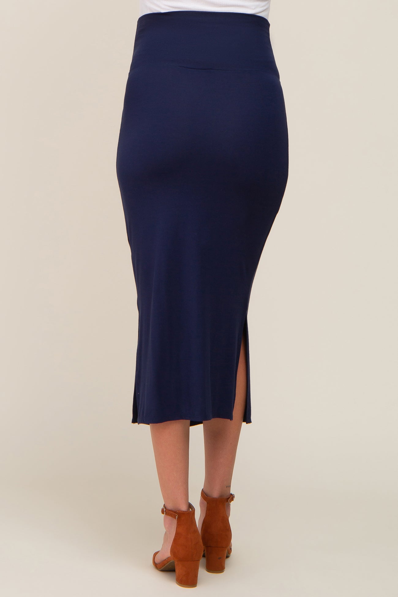 Back view of a woman wearing a navy blue midi skirt with side slits and brown suede block heel sandals