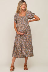 woman wearing a brown floral maternity dress with short puff sleeves and a square neckline, holding her baby bump