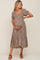 woman wearing a brown floral maternity dress with short puff sleeves and a square neckline, holding her baby bump