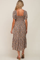 woman wearing a floral print maternity dress with puff sleeves and back cutout, showcasing a baby bump