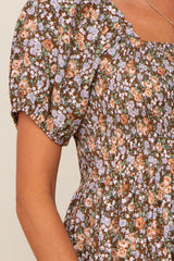 Close-up of a brown floral dress with smocked bodice, puff sleeves, and purple and orange flower pattern