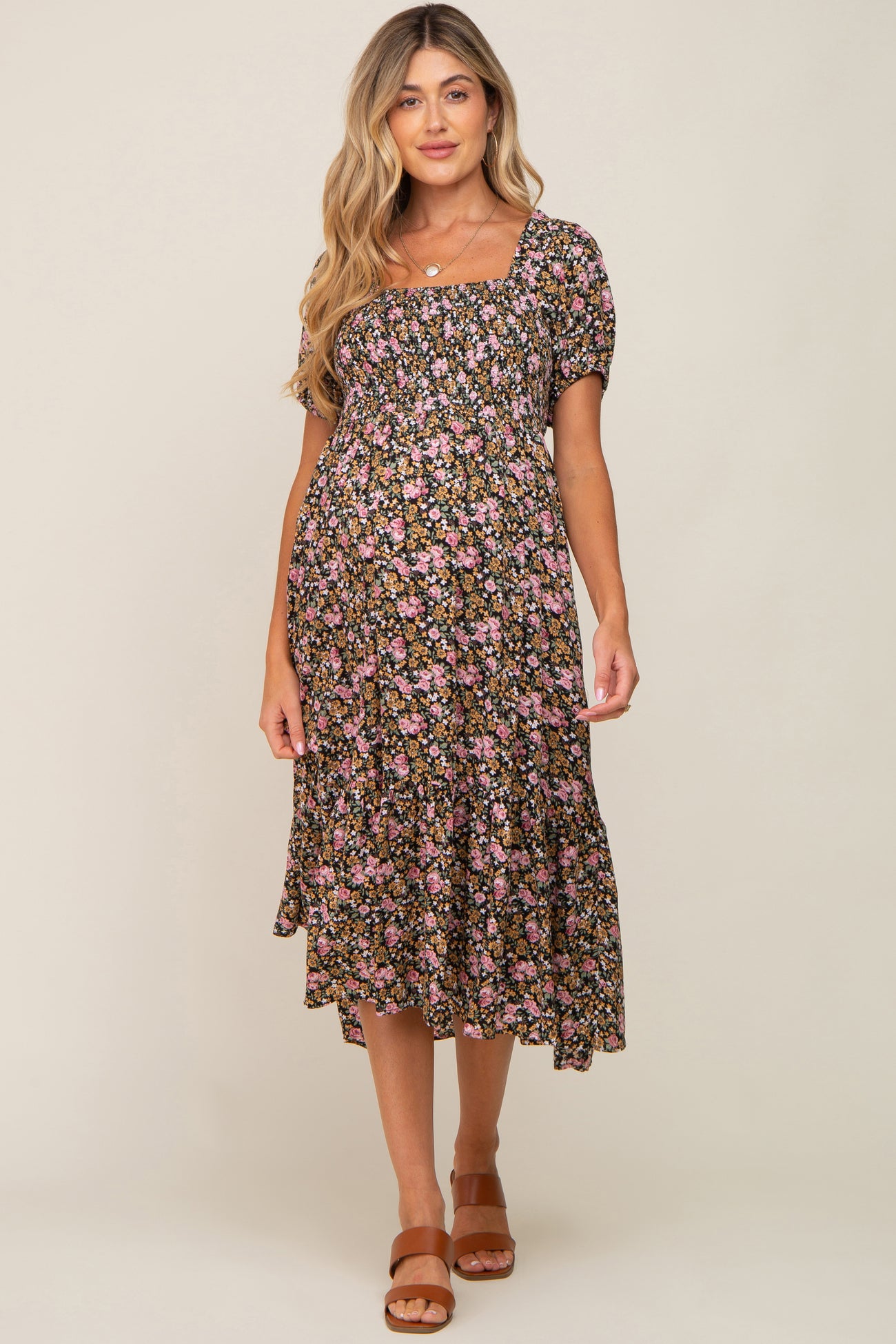 woman wearing a black floral maternity dress with short sleeves and a flowy skirt, featuring a square neckline and a baby bump
