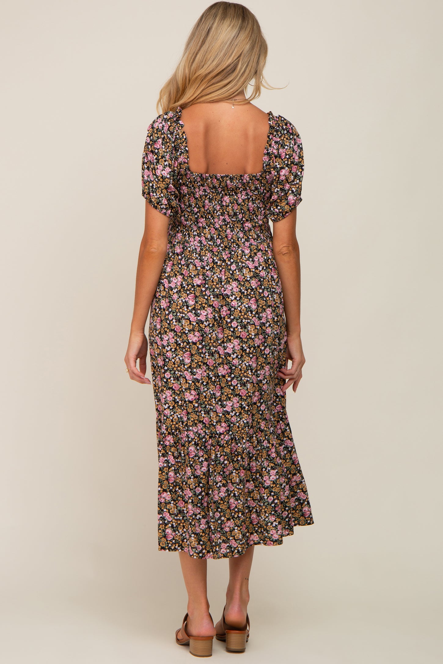 woman wearing a floral black maternity dress with puff sleeves and a square neckline, showing a baby bump from the back
