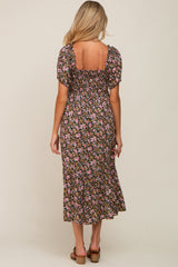 woman wearing a floral black maternity dress with puff sleeves and a square neckline, showing a baby bump from the back
