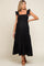woman wearing a black maternity dress with ruffled straps and a tiered skirt, showcasing her baby bump
