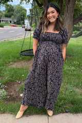woman wearing a navy blue floral maternity maxi dress with short puff sleeves and a visible baby bump
