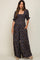 woman wearing a navy floral maternity jumpsuit with short puff sleeves and a square neckline, styled with platform sandals