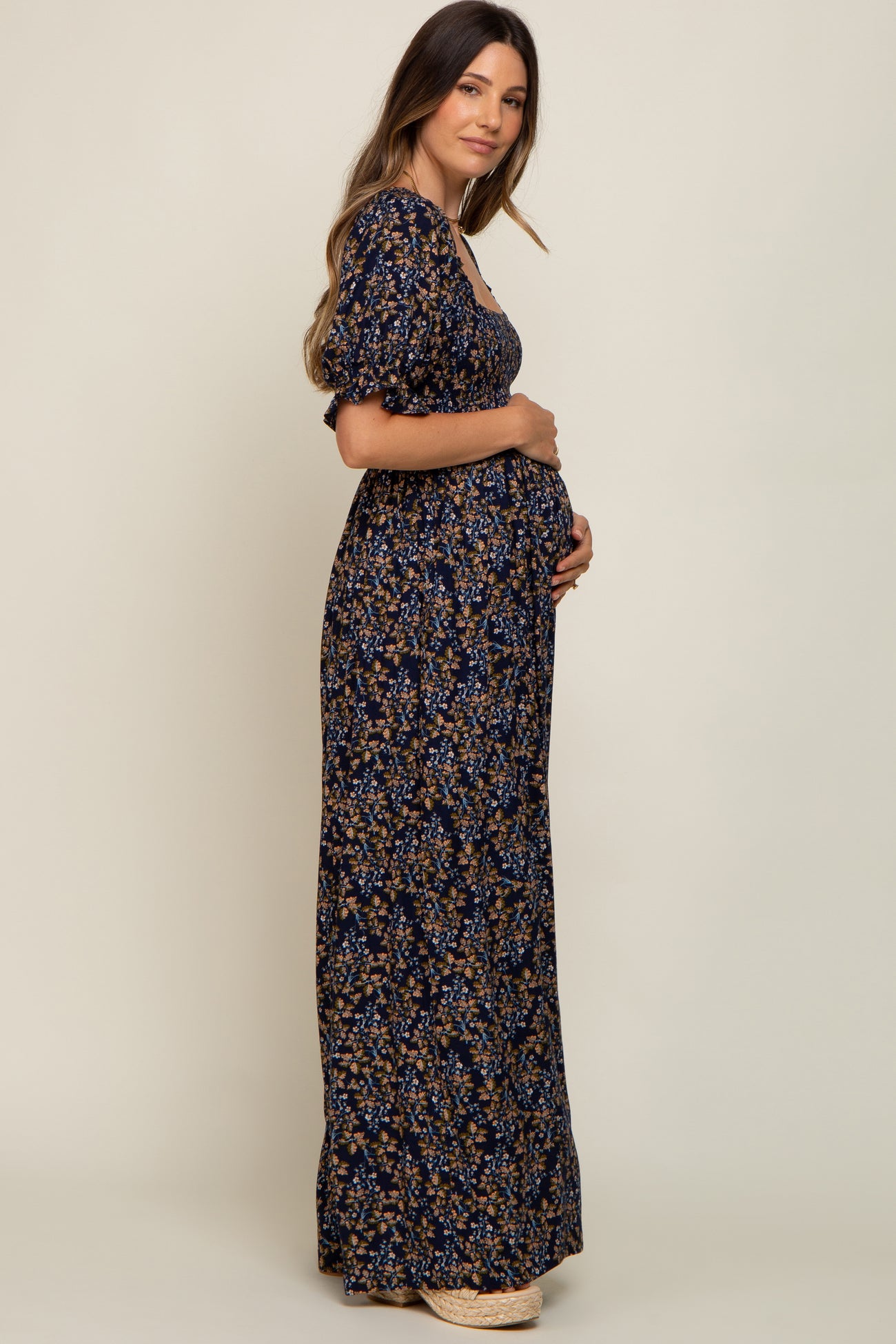 woman wearing a navy floral maternity maxi dress and holding her baby bump