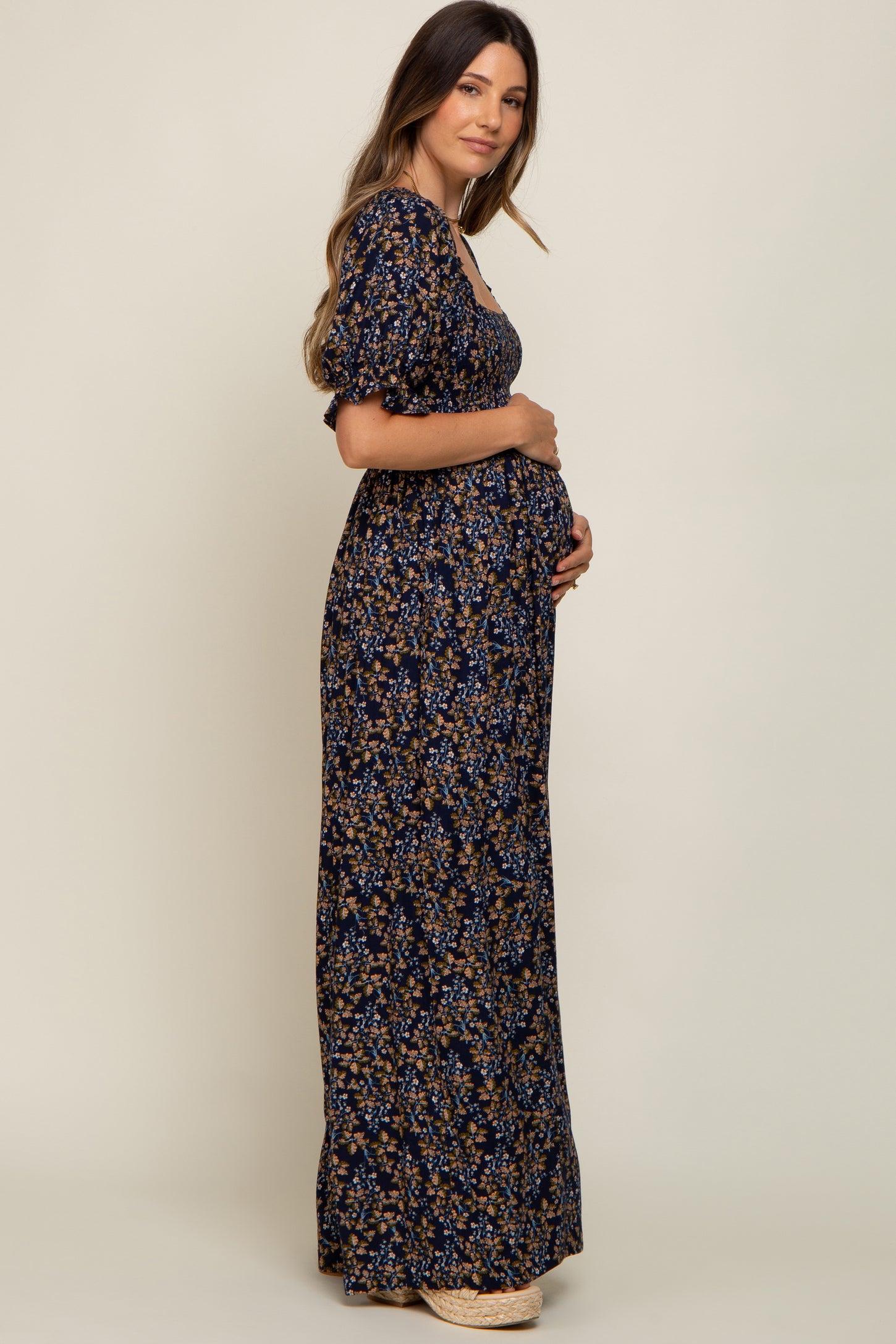 woman wearing a navy floral maternity maxi dress and holding her baby bump