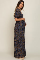 woman wearing a navy floral maternity maxi dress and holding her baby bump