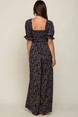 woman wearing a navy blue floral maternity maxi dress with puff sleeves and a smocked back