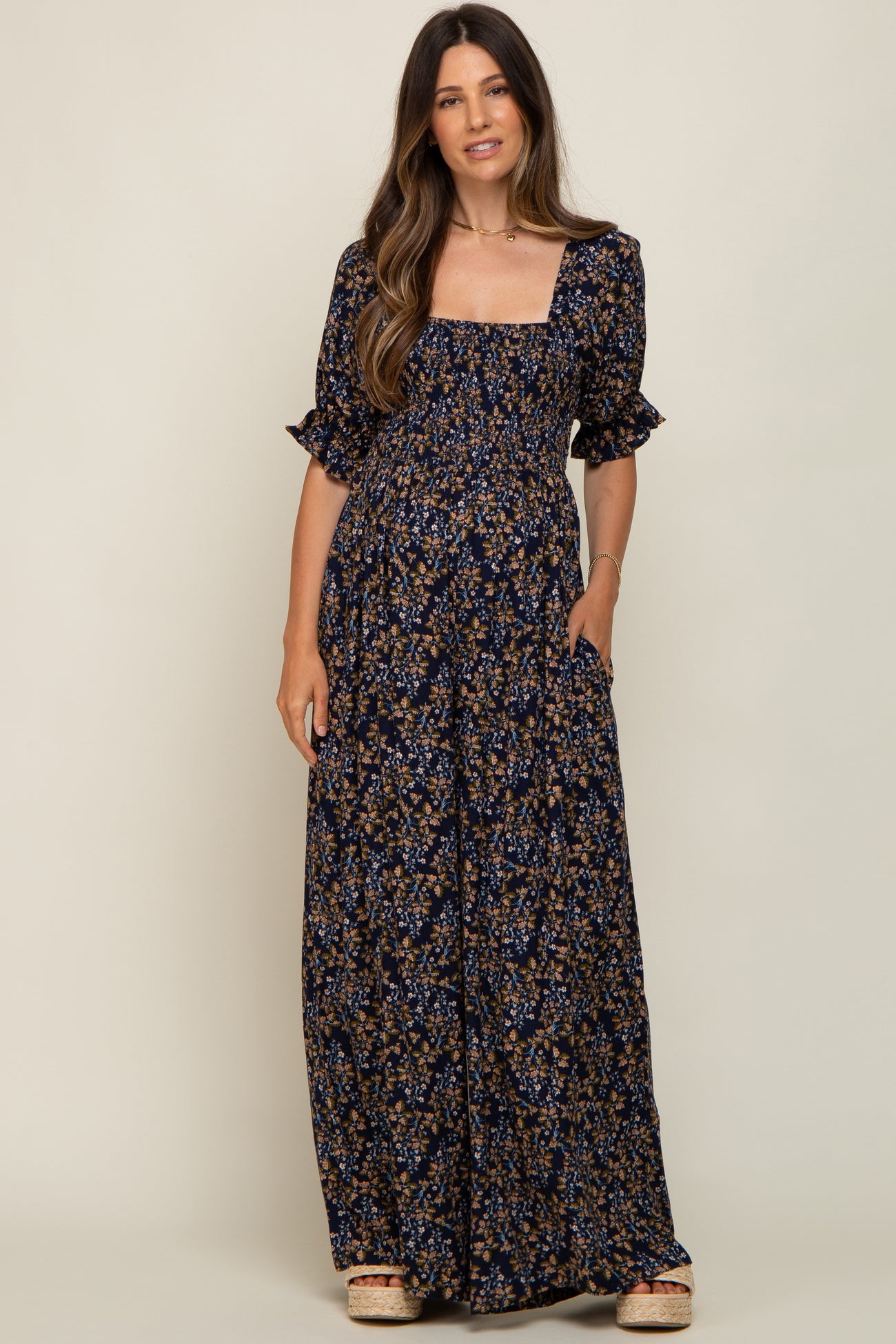 woman wearing a navy blue floral print maternity maxi dress with short sleeves and square neckline, holding pockets