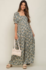 woman wearing a floral maternity maxi dress with puff sleeves and a square neckline, holding a white bag