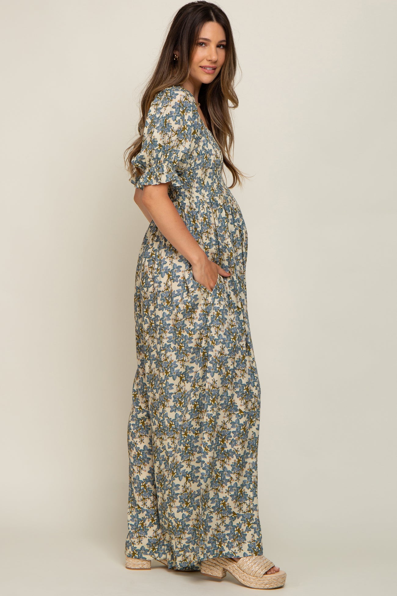 woman wearing a floral print maternity maxi dress with short sleeves and pockets, showing her baby bump