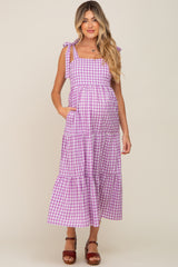 woman wearing a purple gingham maternity maxi dress with tie straps and pockets, showcasing her baby bump